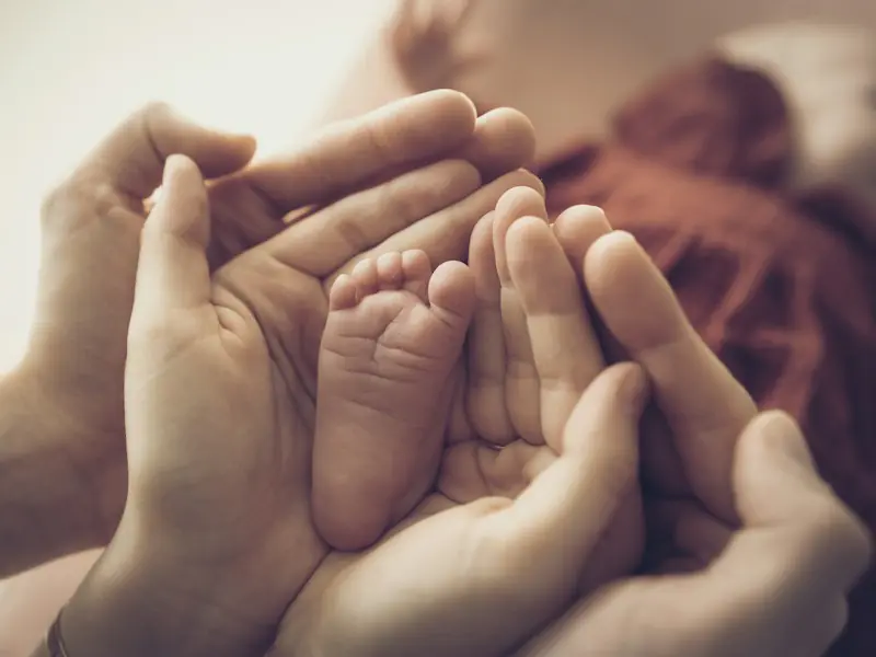 Pieds d’un nourrisson dans des mains d’adulte