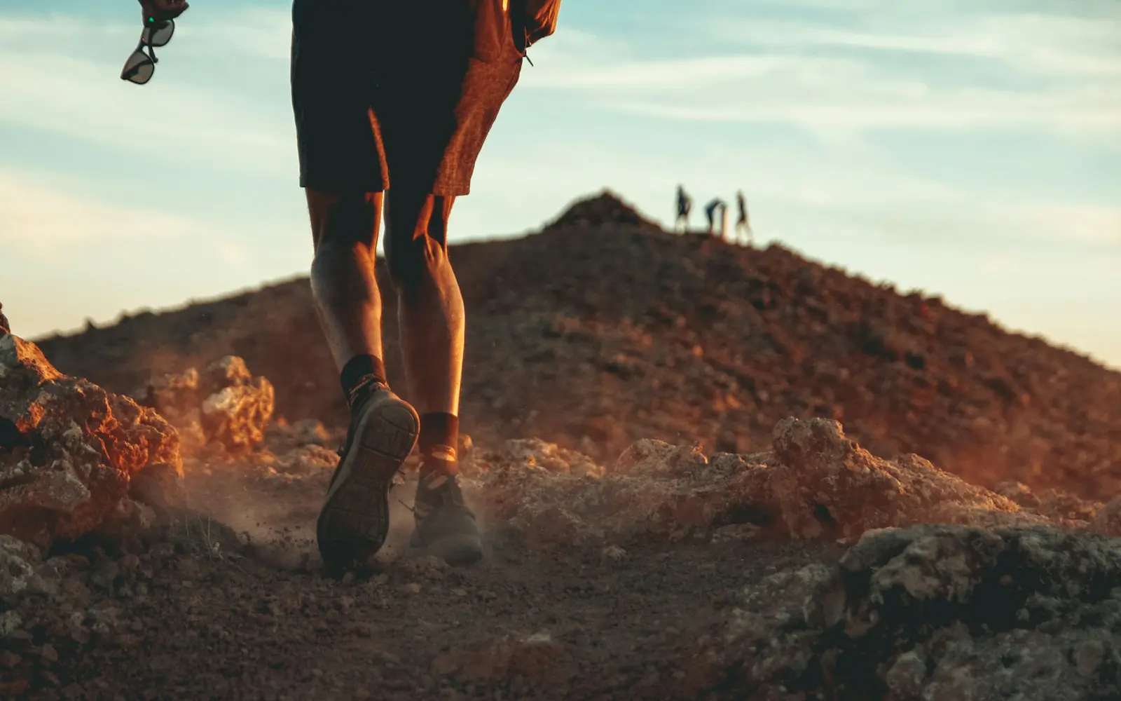 Jambes d’un coureur sur un sentier de colline, au soleil couchant