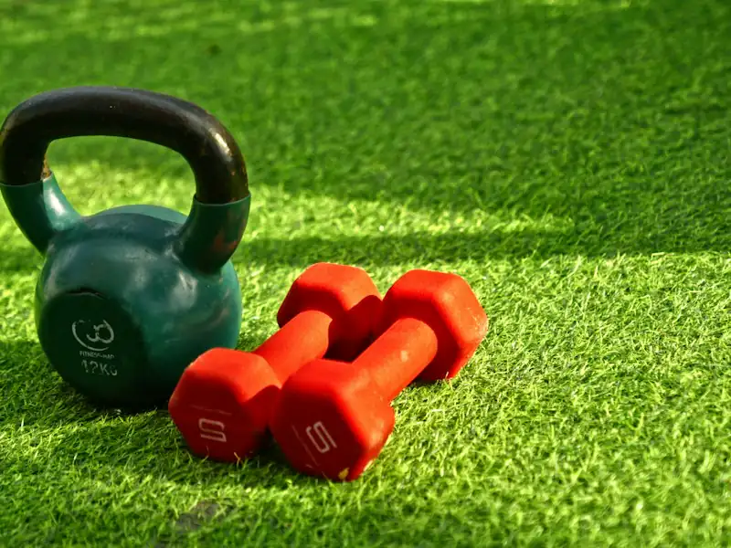 Kettlebell et haltères posés sur le gazon
