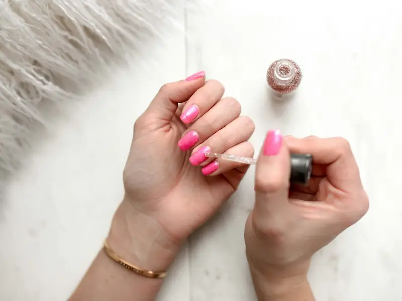Pose de vernis rose sur des ongles