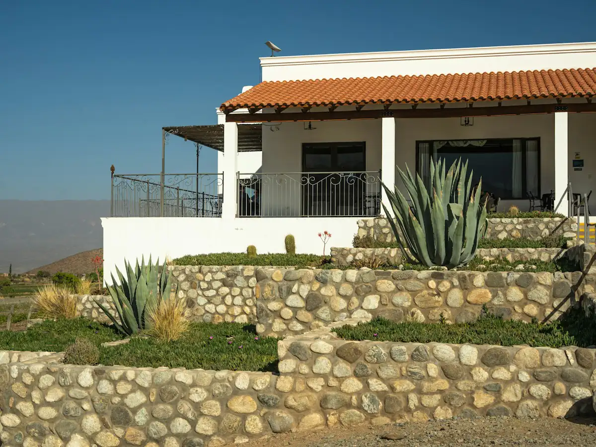 Restanques en pierre plantées d’agaves devant une maison blanche