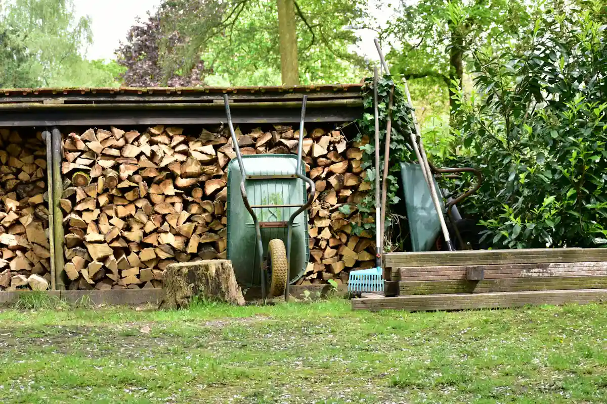 Brouette et bois de chauffage rangés contre l’abri du dépôt