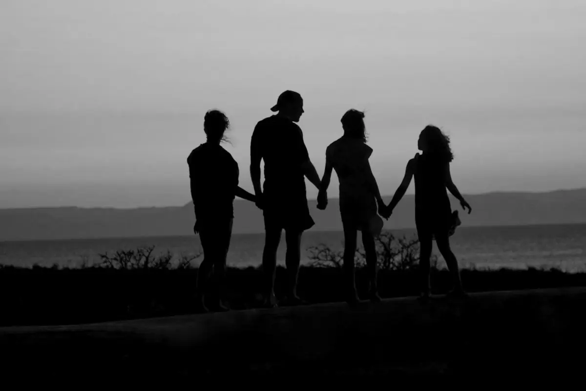 Quatre silhouettes main dans la main au crépuscule