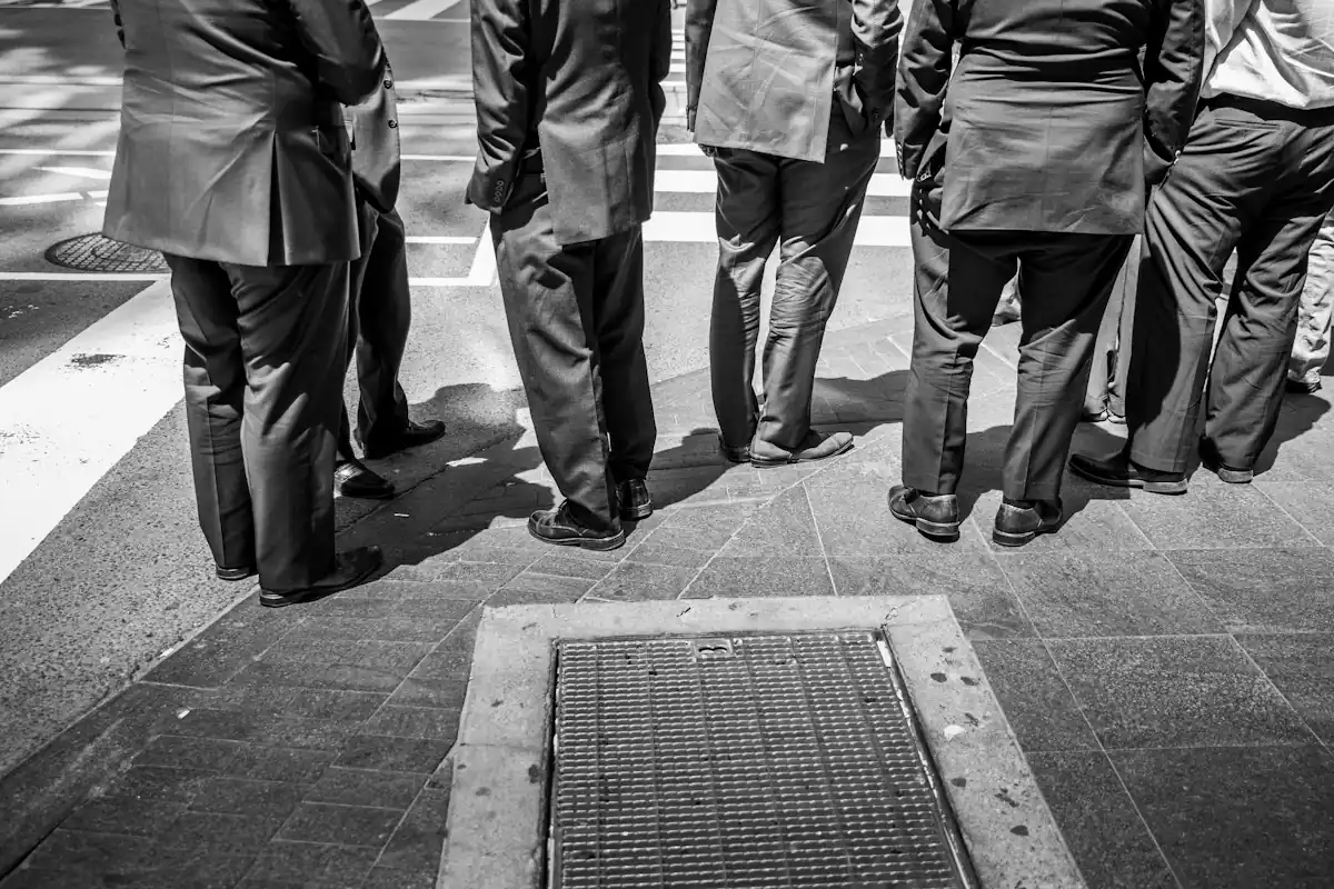 Groupe en costumes vu de dos, sur un pavé ensoleillé