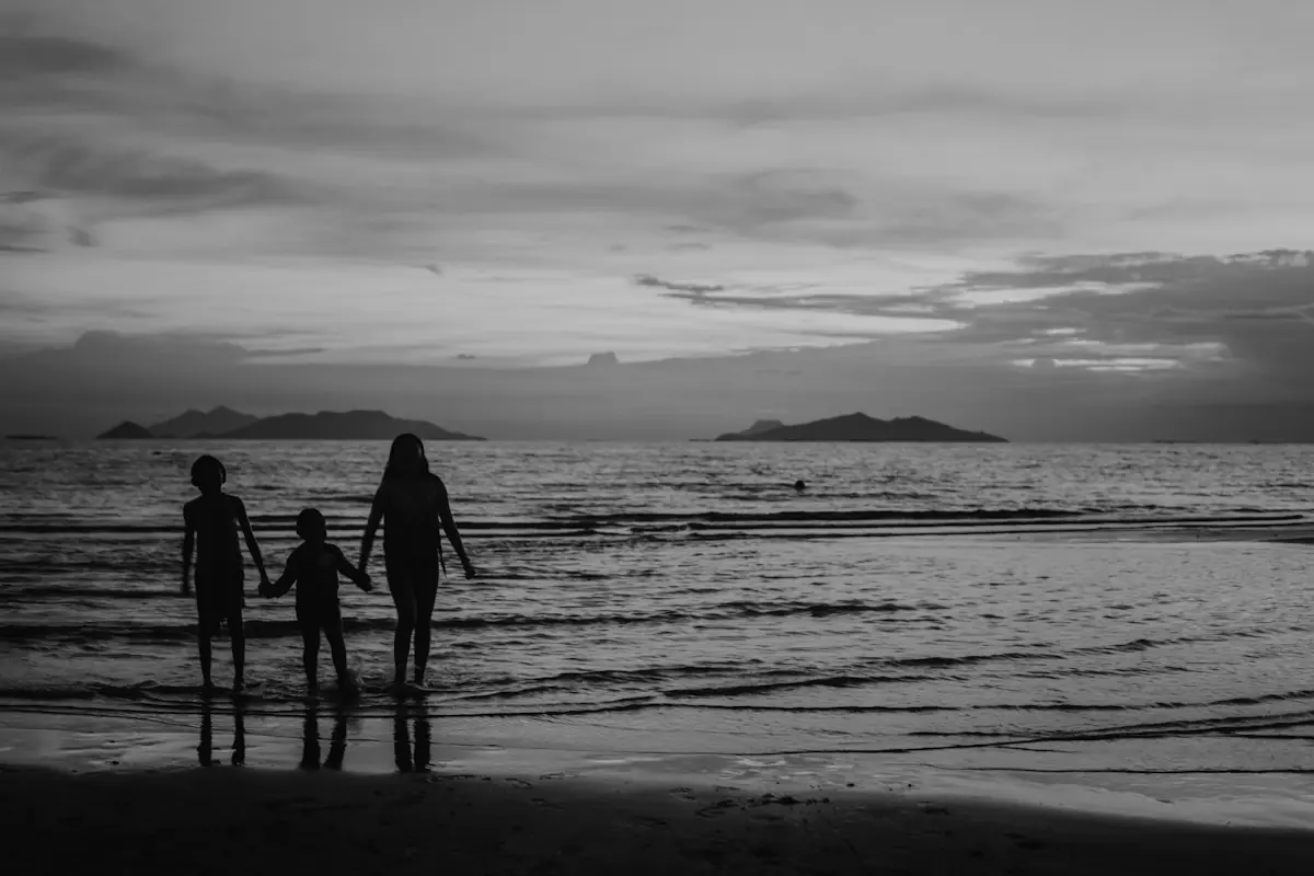 Une mère et deux enfants face à la mer, en silhouette