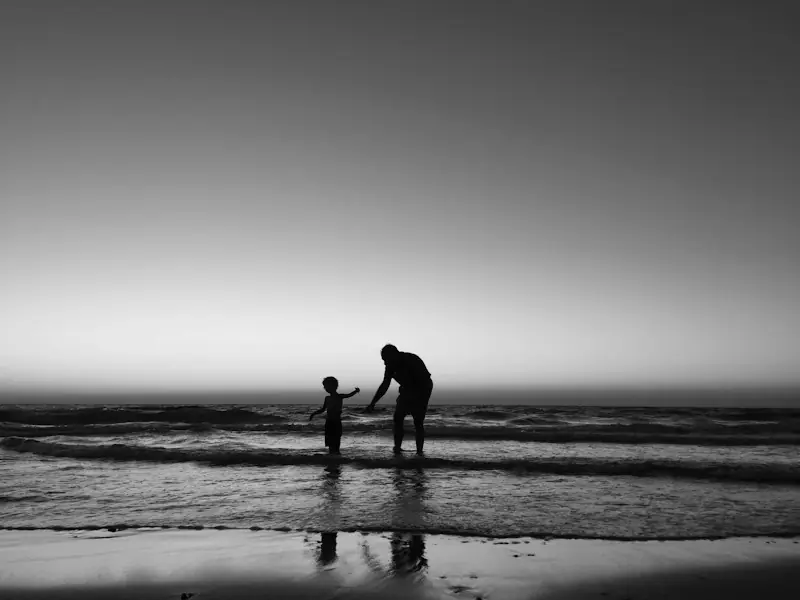 Silhouettes d’un parent et d’un enfant au bord de la mer